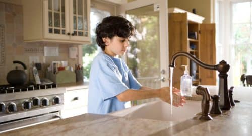 boy in blue polo shirt standing in front of sink