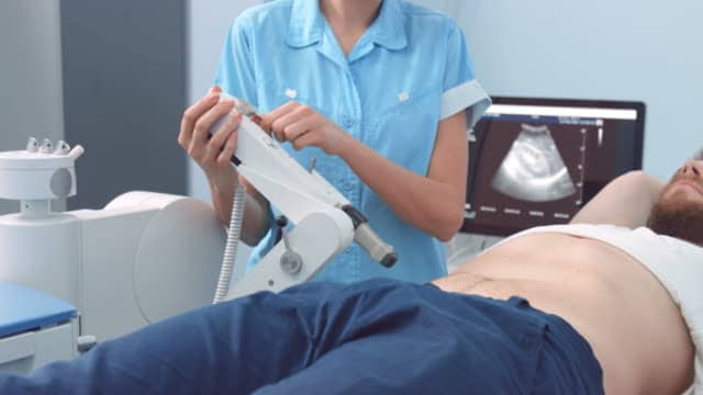 Female assistant adjusts ultrasound transducer before kidney lithotripsy procedure | Extracorporeal shock wave lithotripsy for remove the stones from kidney.