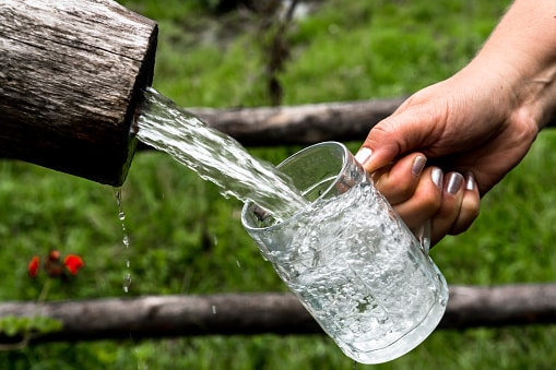 Big Glass Filled With Clear Mountain Drinking Water From A Wooden Spring