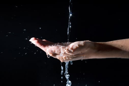 "water pxouring on a female hand, on a black background."