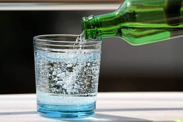 Pouring cold mineral water in the glass close up image.